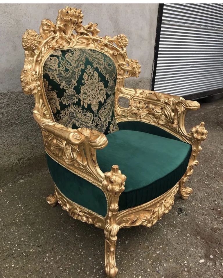 Ornate gold baroque-style chair with green velvet seat and patterned backrest on pavement