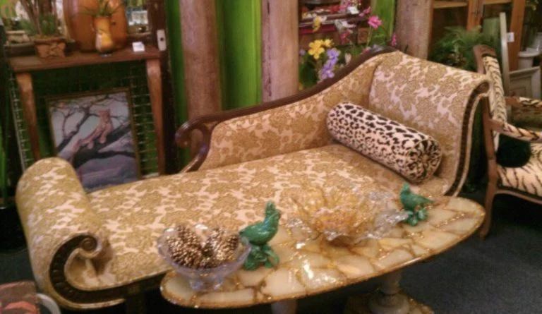 Gold floral chaise lounge with patterned pillows and a glass-topped coffee table in a cozy living room