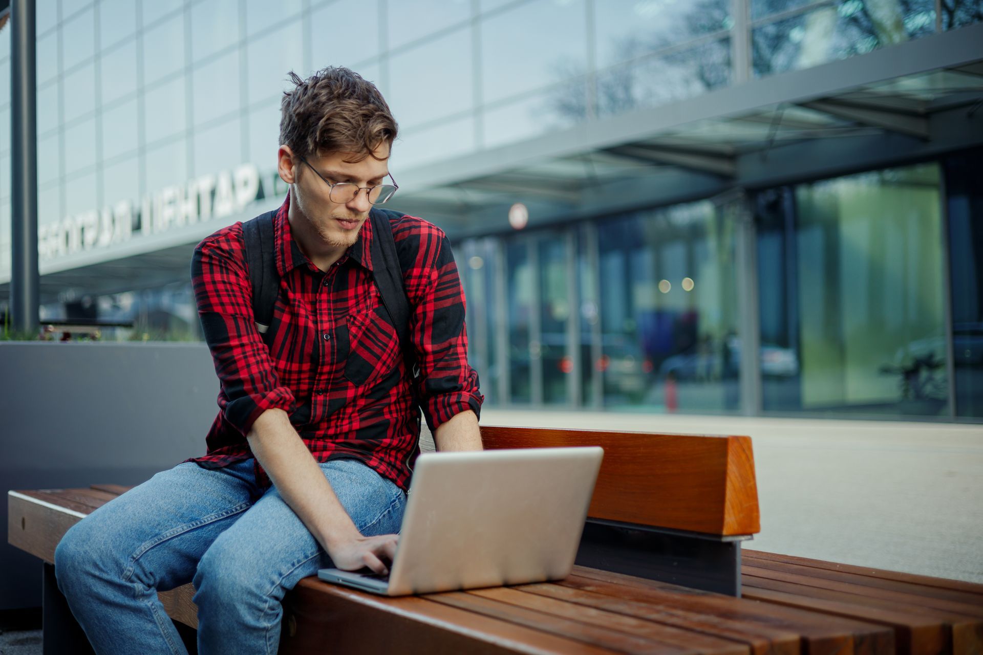 Ein junger Mann sitzt auf einer Bank und benutzt einen Laptop.