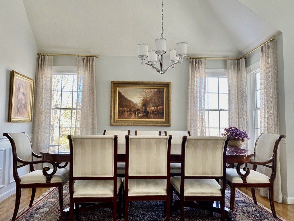 Dining room with table, chairs, art, windows, chandelier, and patterned curtains.