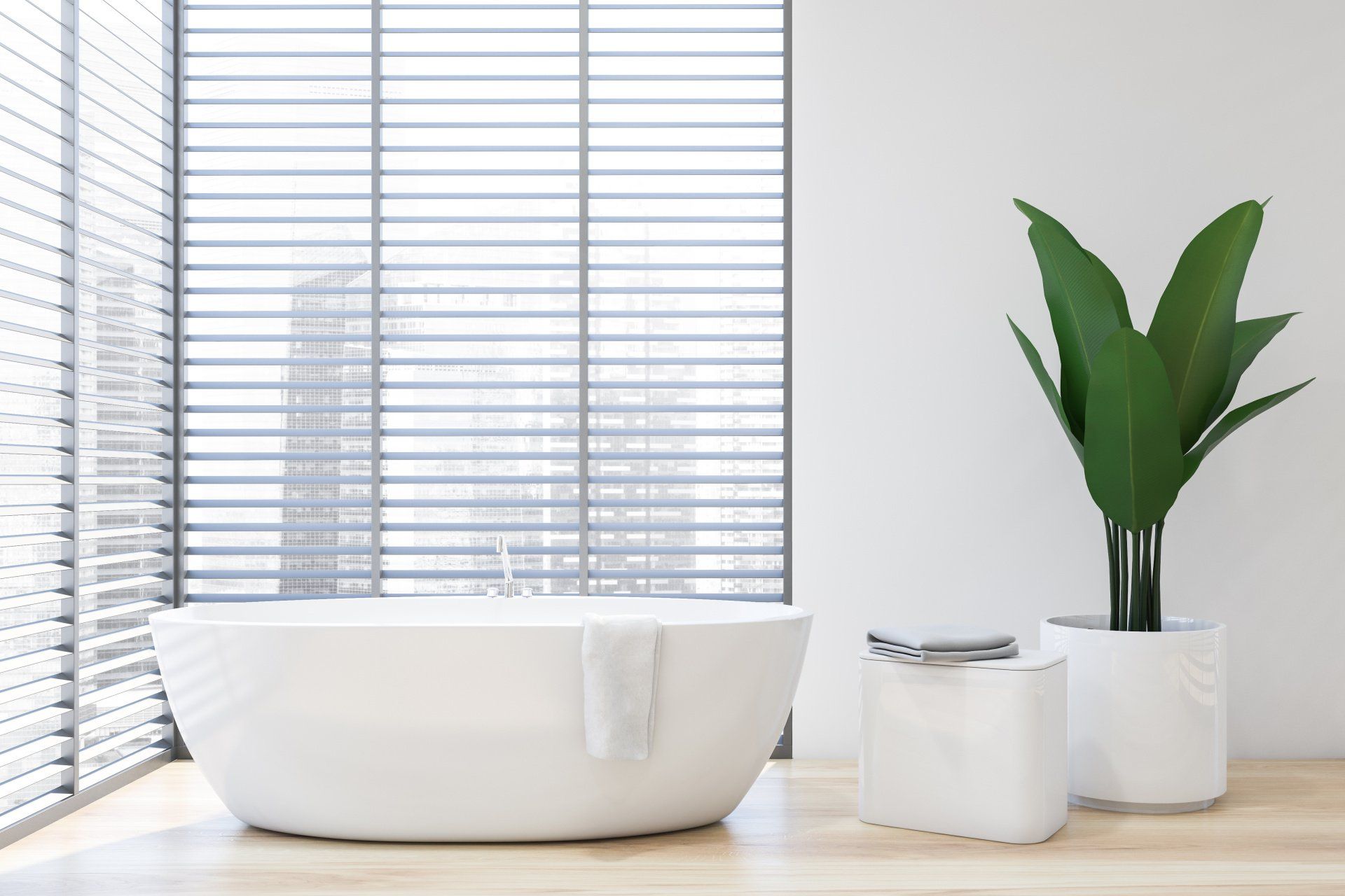 A modern bathroom with a white tub, plant, and blinds.
