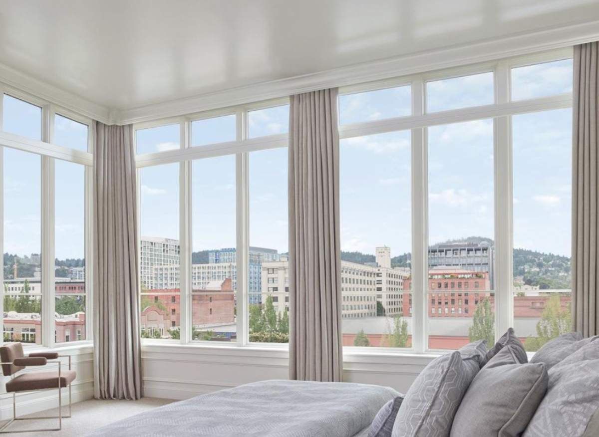 a bedroom with a large bed and lots of windows with roller shades and drapery Simply Windows.