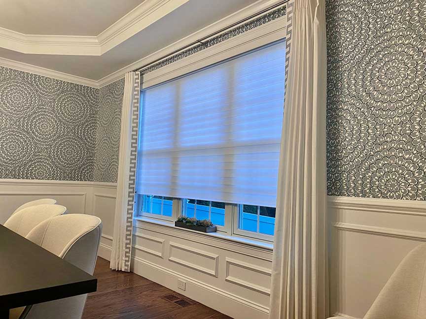a dining room with a table and chairs and a large window with custom draperies Simply Windows.