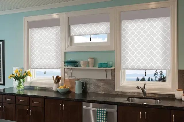 Kitchen with three windows, roller shades, dark cabinets, and blue wall.