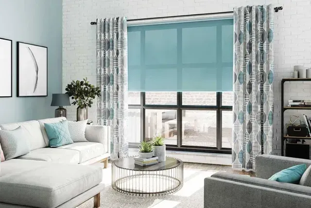Living room with blue curtains and shades; white sofa, and a glass coffee table.
