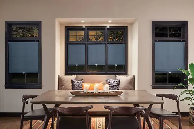 Dining room with dark-framed windows, blue shades, and a wooden table with chairs.