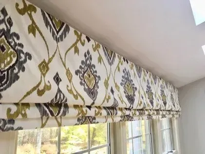 Roman shade with a cream, gray, and gold ikat print above a window.