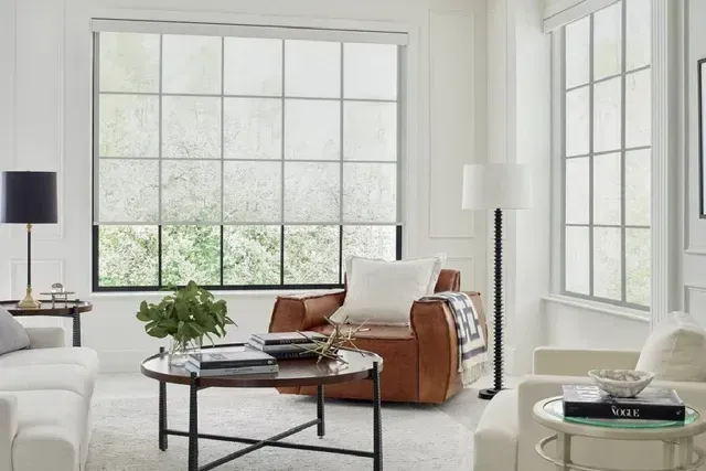 Living room with large windows, brown leather armchair, white sofa, and round coffee table.