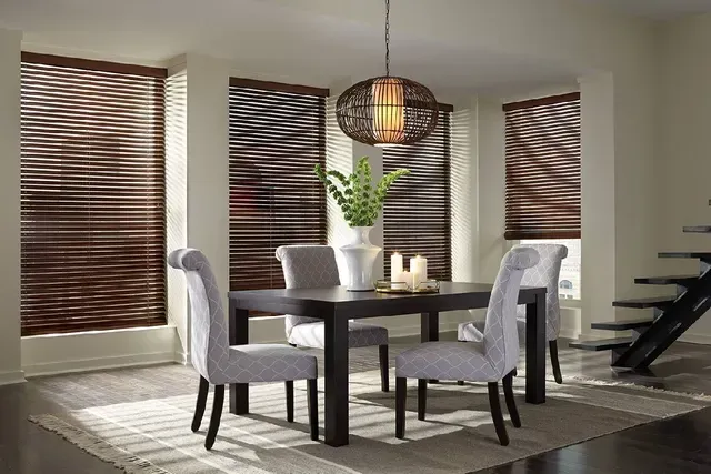 Dining room with dark wood blinds, table, chairs, and hanging light.
