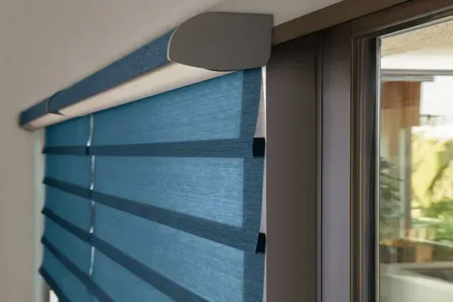 Blue and tan layered window shade installed on a window frame, partially open.