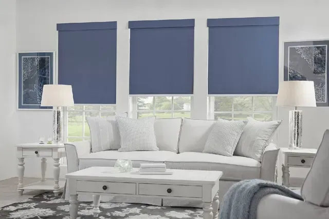 Living room with white furniture, blue shades, and window art.