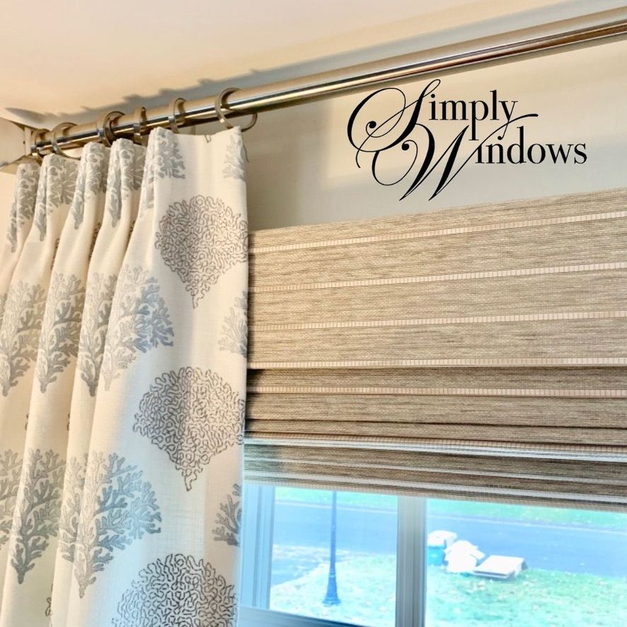 Beige Roman shade and patterned curtains over a window in a home interior