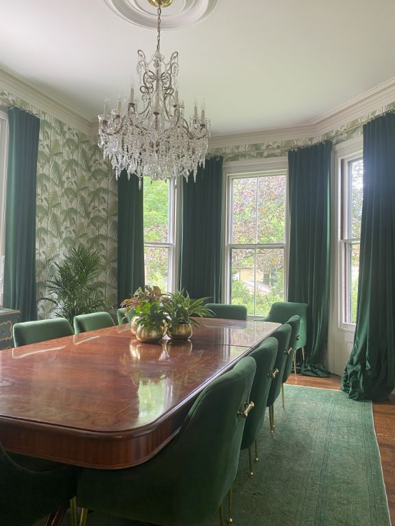 a dining room with a long table and green chairs and a chandelier with elite window treatments Simply Windows.