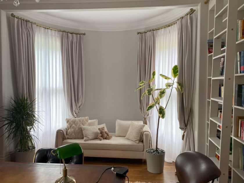 a living room with a couch , desk , chair and bookshelf and elite window treatments Simply Windows.