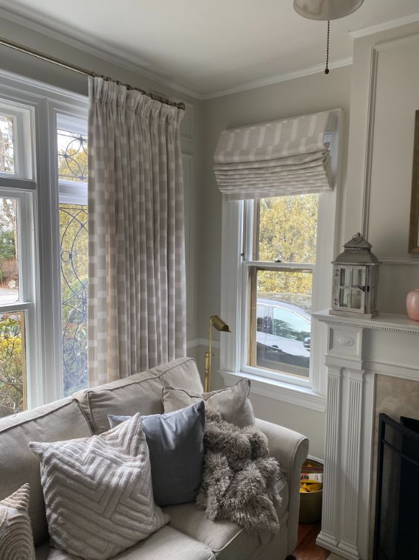 a living room with a couch , fireplace , and two windows with elite window treatments Simply Windows.