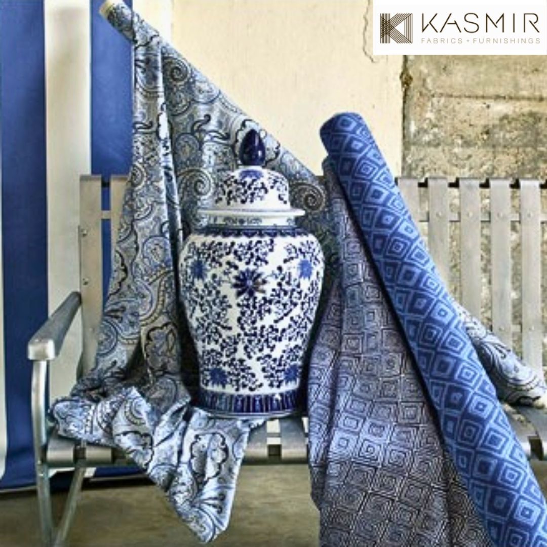 a blue and white vase is sitting on a chair next to a designer fabric rolls Simply Windows.