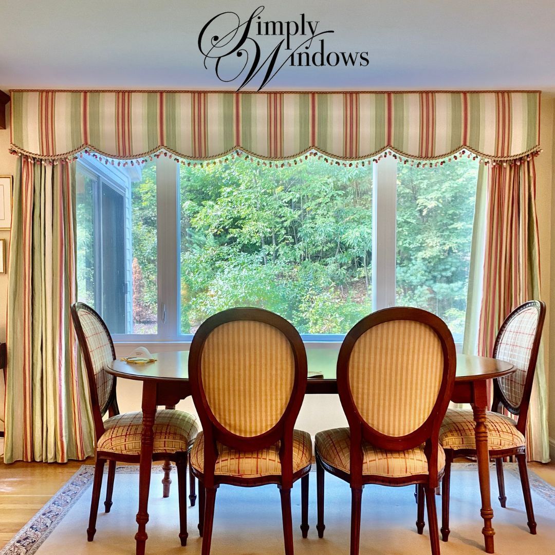 Dining room with ornate striped drapes, large window, and upholstered chairs around a table.