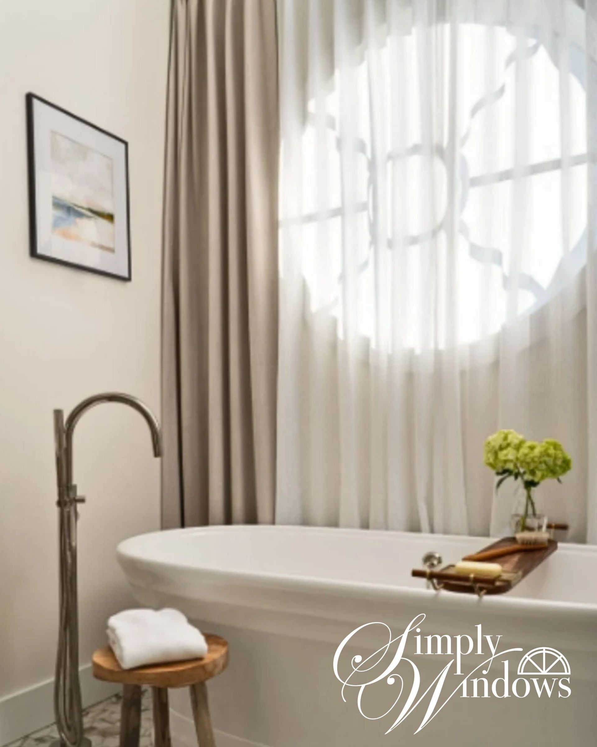 Bright bathroom with a freestanding tub, sheer curtains, and a small tray of flowers and tea on the tub edge
