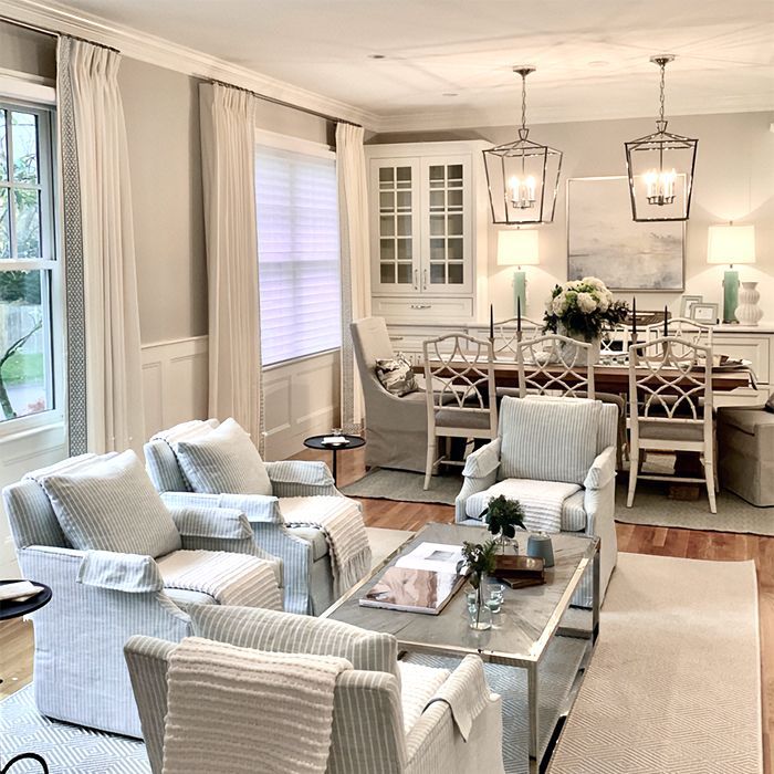 Living room with neutral tones, four armchairs, a coffee table, and dining area in the background.