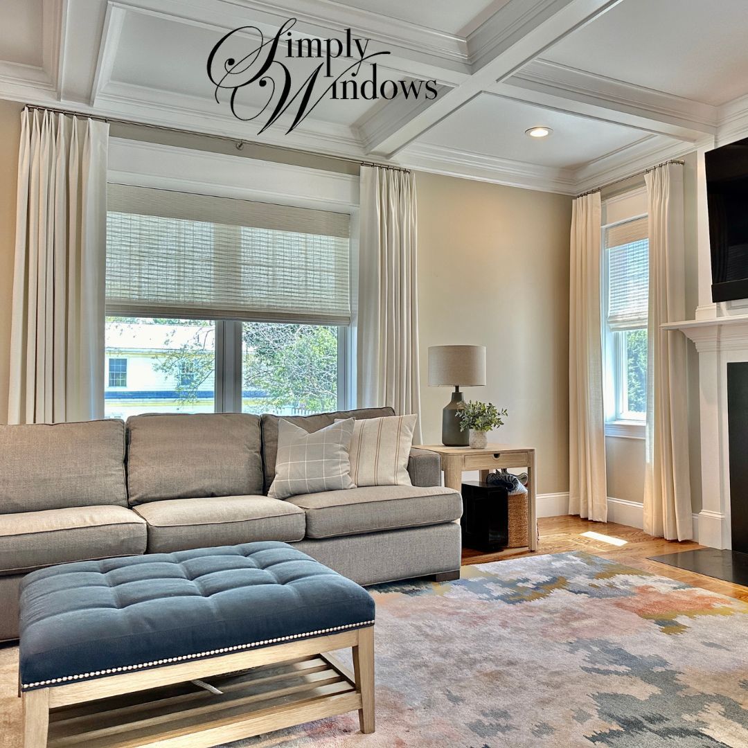 Bright living room with gray sectional,  large windows, and layered drapery.