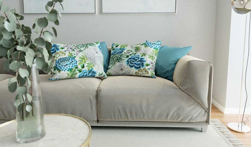 A grey couch has Alendel blue floral fabric pillows on it.