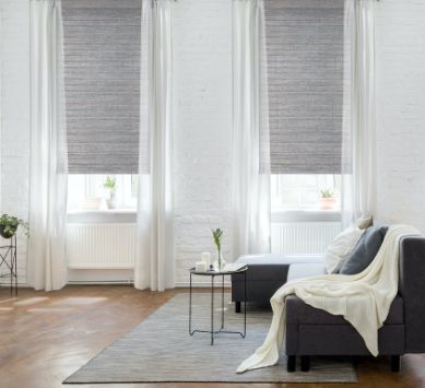 A clean, white room with drapes, pillows and blankets by Pro Design fabrics.