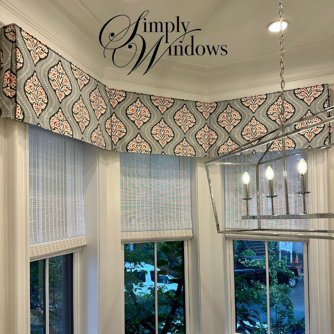 Curved bay window with custom blinds, patterned valance, and a hanging chandelier overlooking greenery