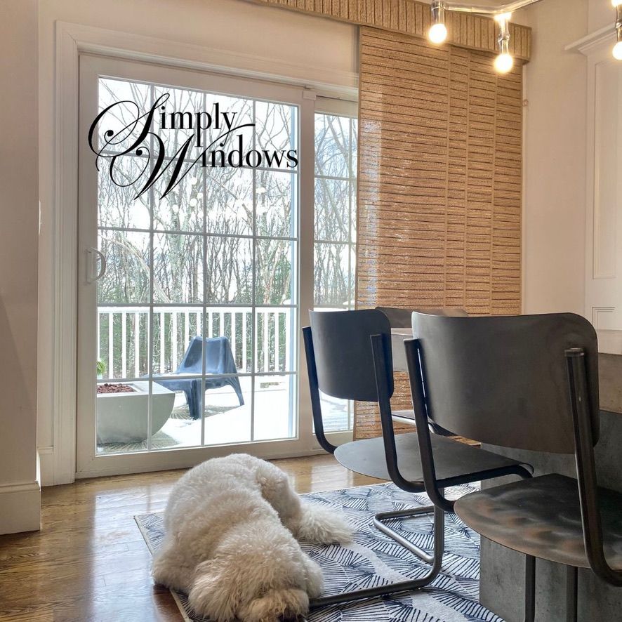 Cozy dining room with sliding glass doors, woven wall panel, modern chairs, and a fluffy dog on the floor