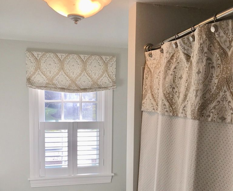 Bathroom with window, patterned valance with shutters, and beige shower curtain