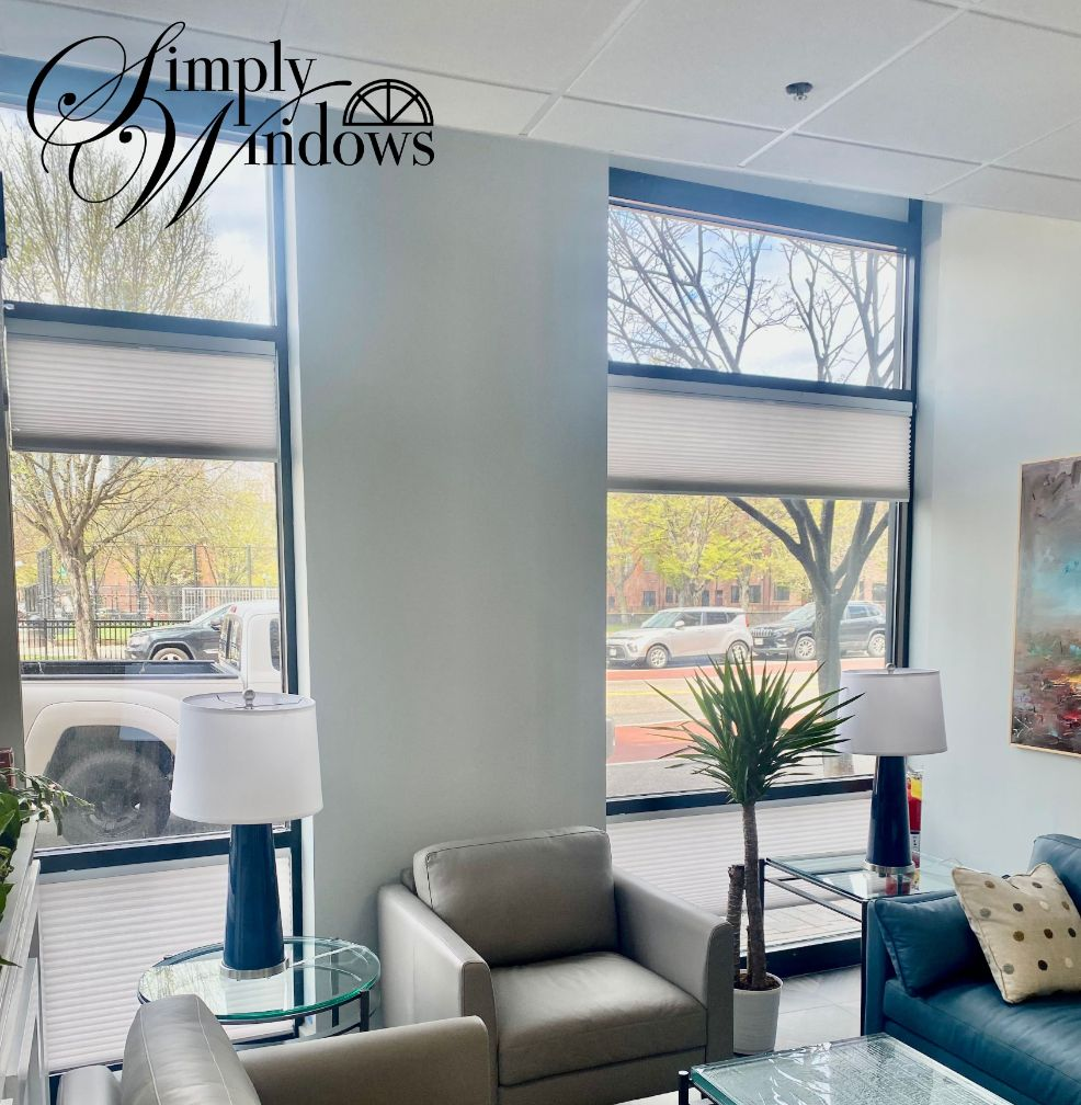 Bright showroom with large windows, gray chairs, white lamps, and top-down bottom-up shades.