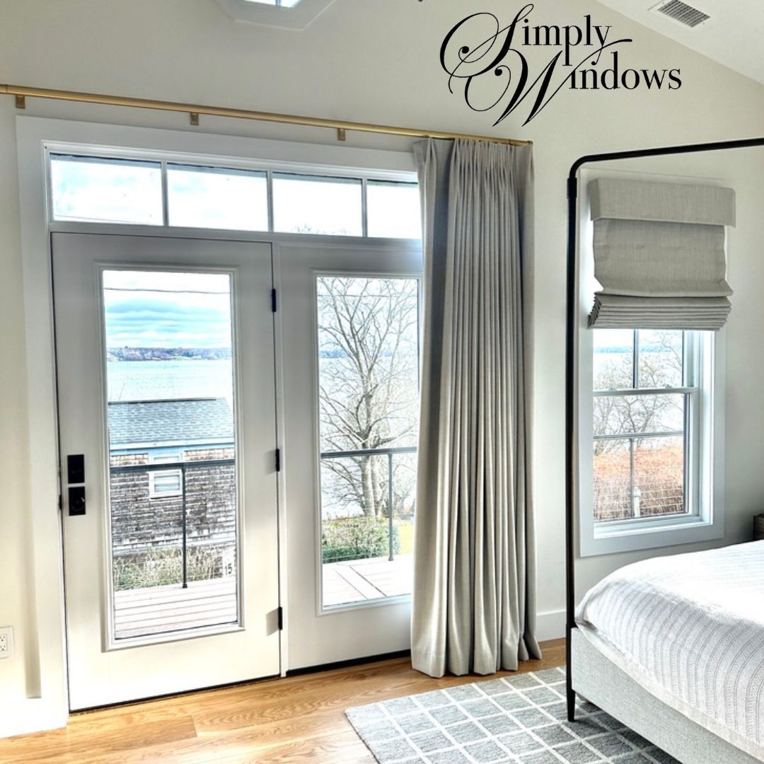 Bedroom with white French doors, gray drapery, and a view through the windows.
