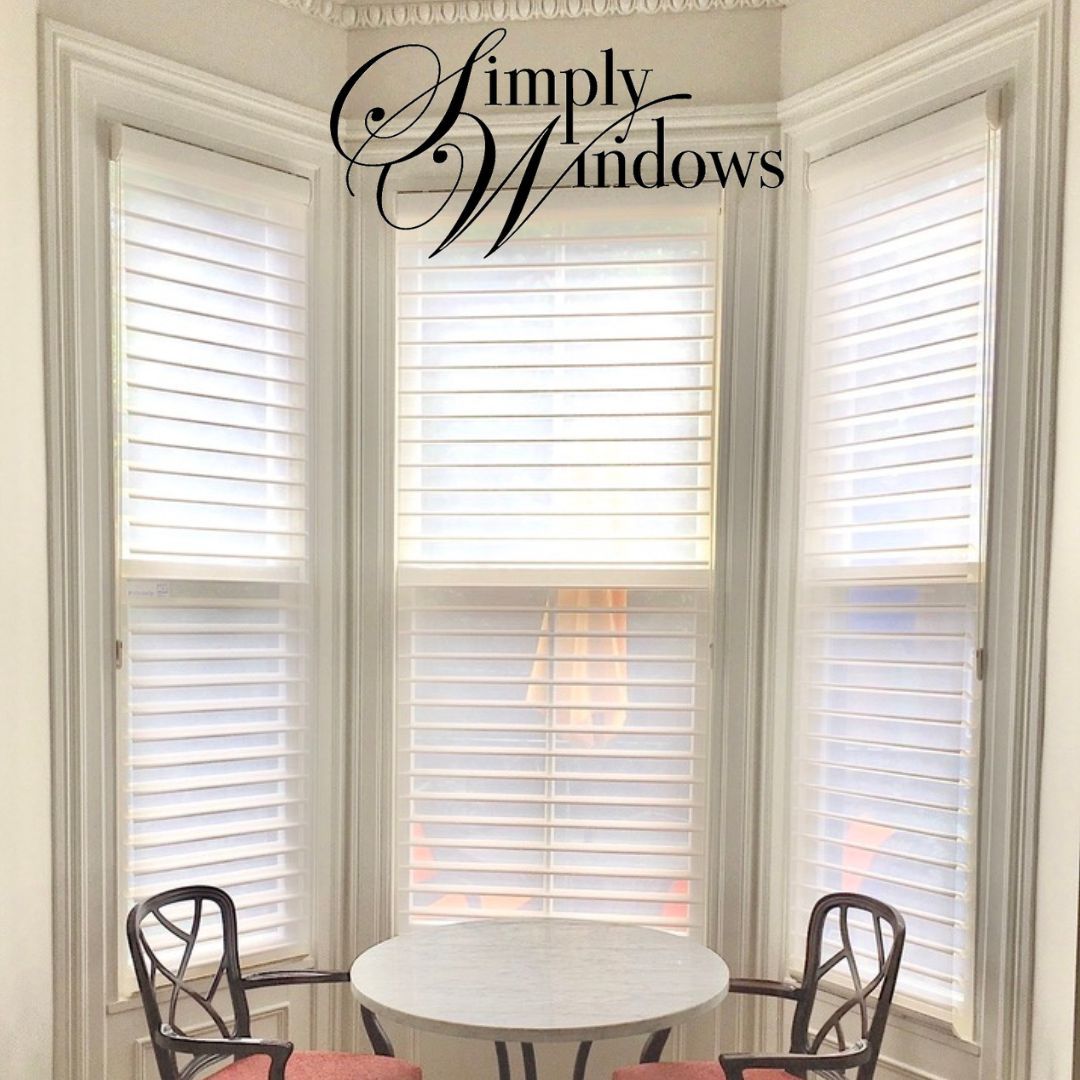 Bright bay window with white plantation shutters and a small round table with two chairs