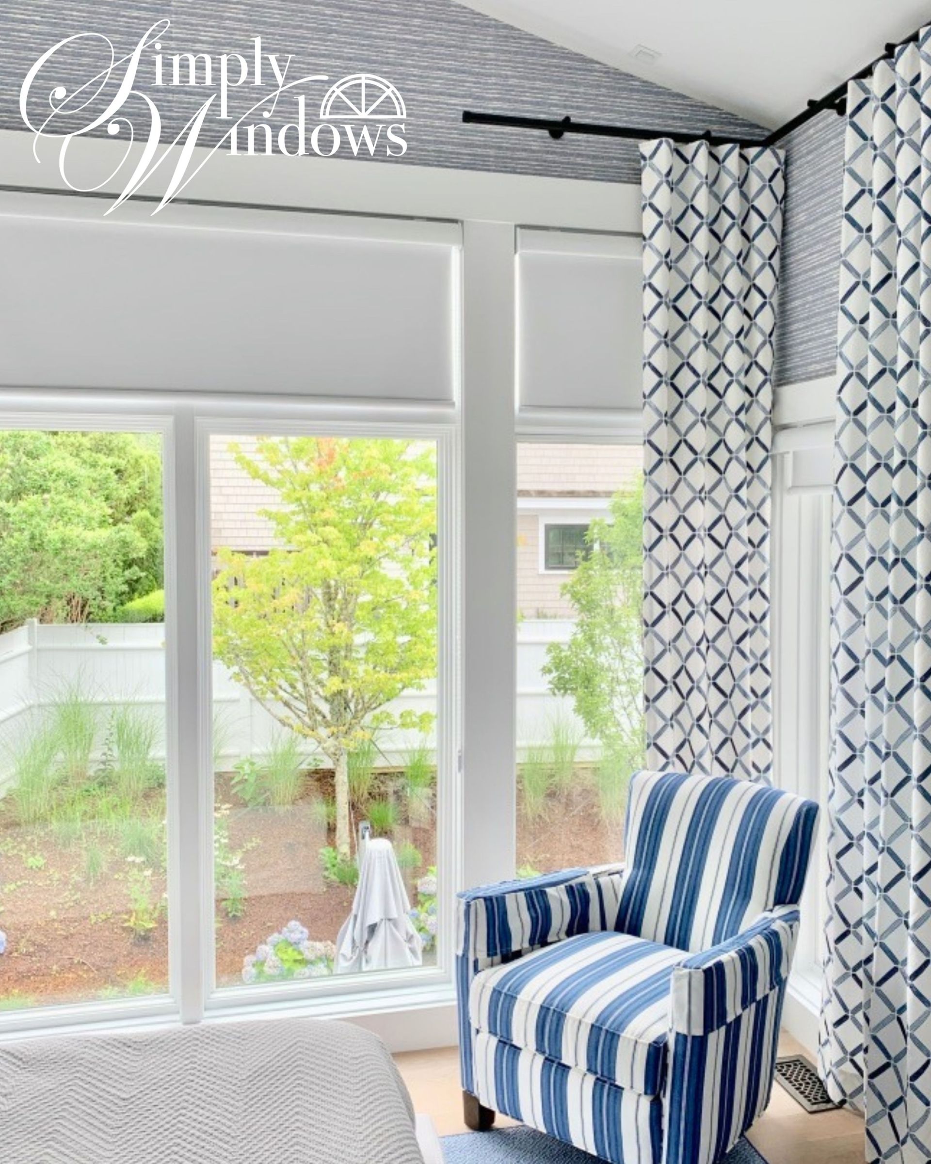 Blue-striped armchair by sliding glass doors with roller shades and custom drapery. 