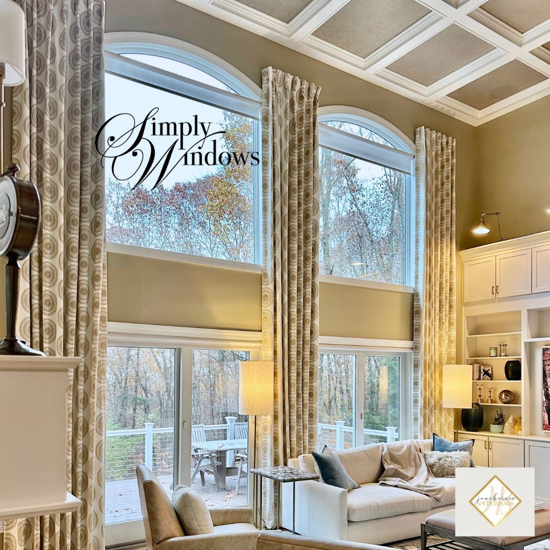 Bright living room with floor-to-ceiling windows, patterned custom drapery, and vaulted ceiling with geometric trim