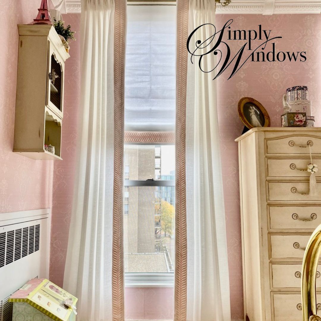 Pink bedroom corner with custom drapery, window seat, and cream dresser beside a wall mirror