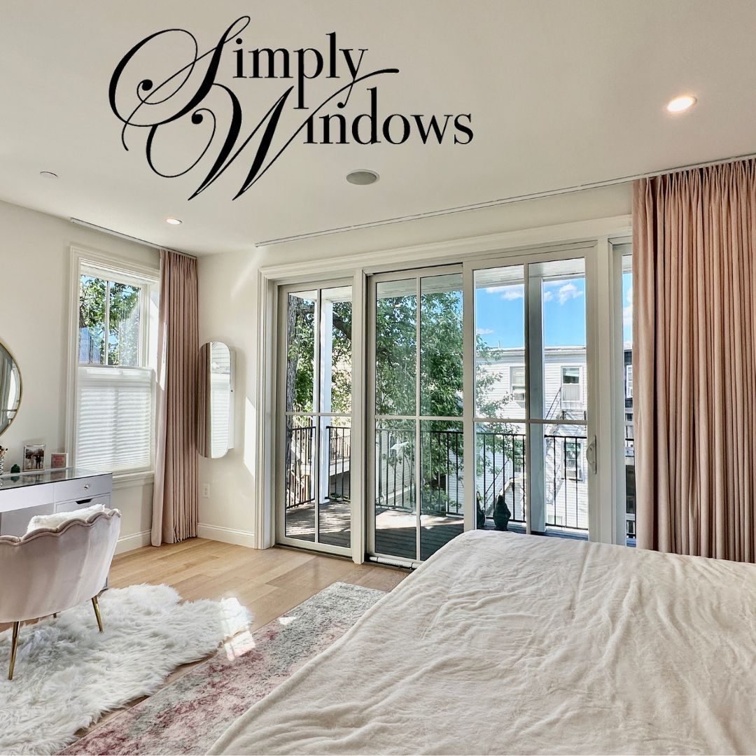 Bright bedroom with large windows, pink drapery, and white bedding overlooking greenery
