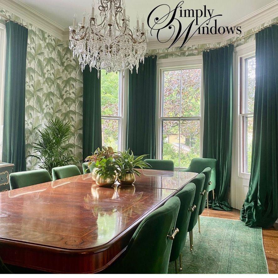 Elegant dining room with green drapes, crystal chandelier, and polished wooden table by bright windows