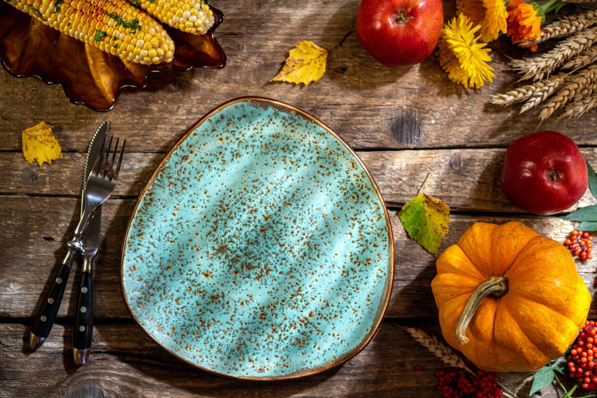 a blue plate is sitting on a wooden table surrounded by pumpkins , apples , and corn Simply Windows.