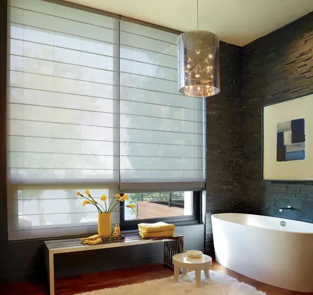 Modern bathroom with window, bathtub, and decorative lighting. Black accent wall, white tub and rug.