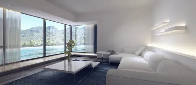 Modern white living room with panoramic view of ocean and mountains.