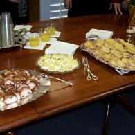 Assorted pastries, cookies, and drinks arranged on a wooden table at a meeting