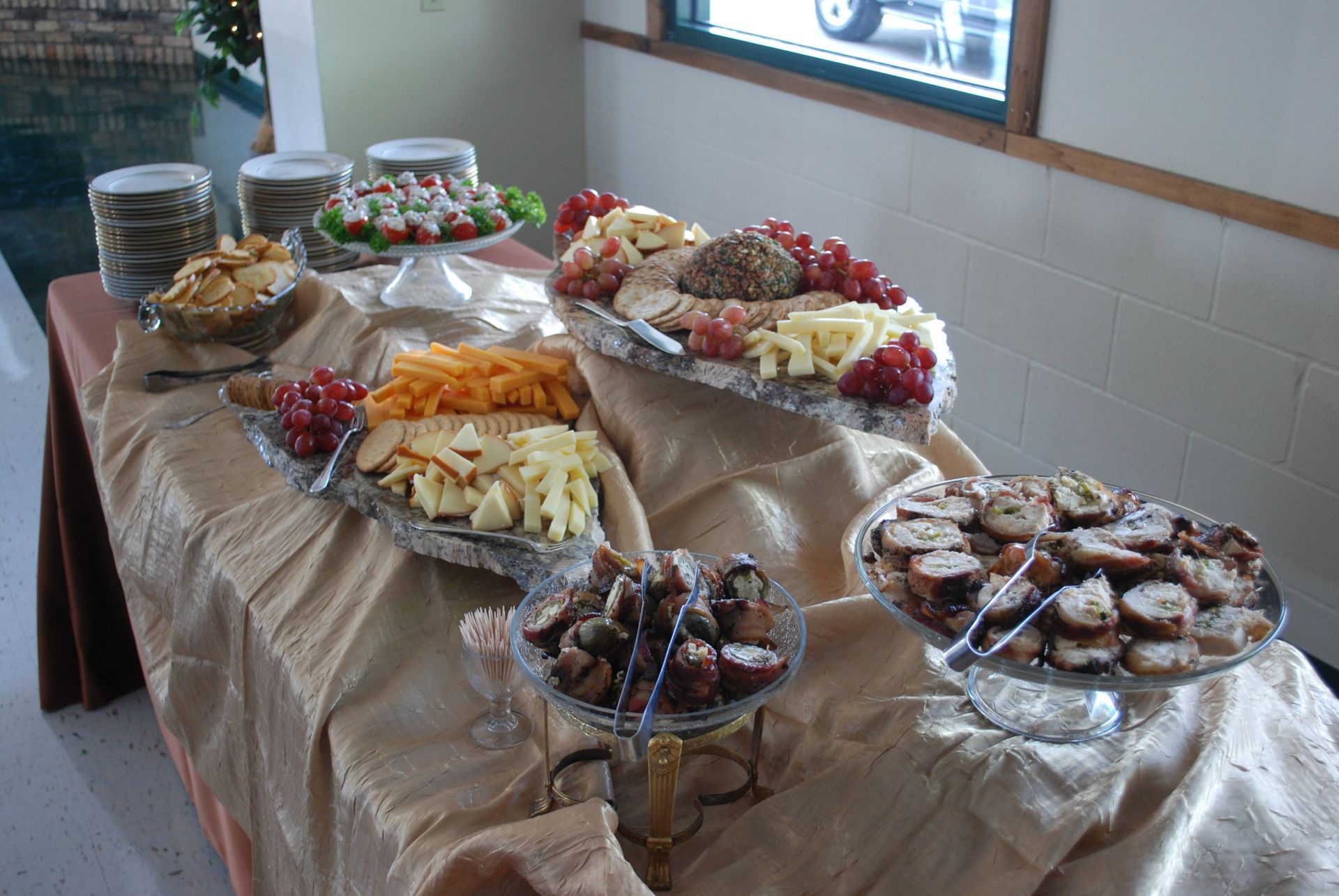 Buffet table with platters of assorted desserts, fruit, and pastries in a tiled dining room