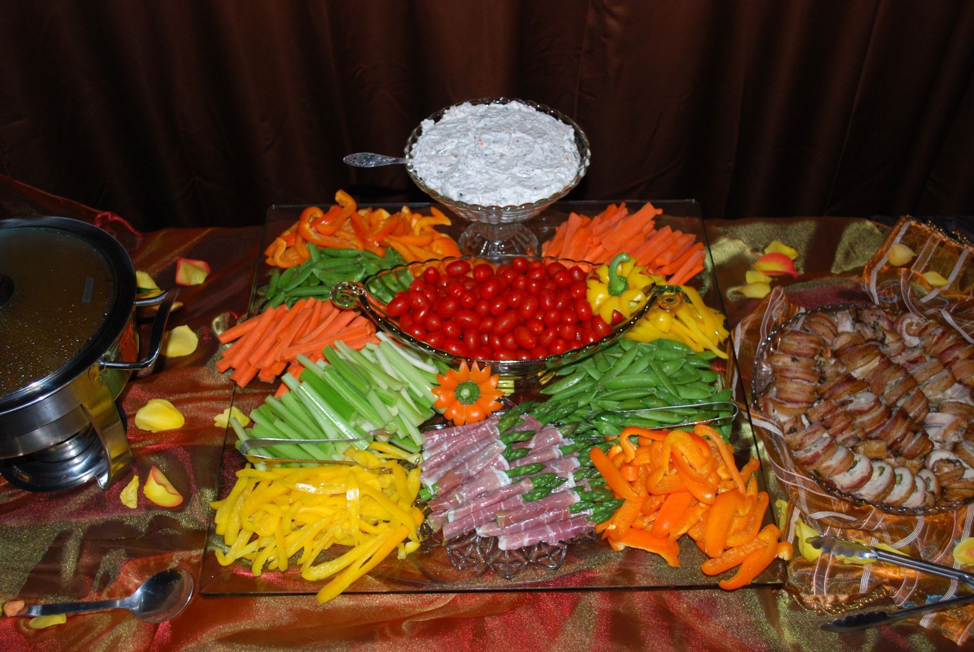 A colorful buffet of sliced vegetables, cherry tomatoes, and dishes arranged on a table