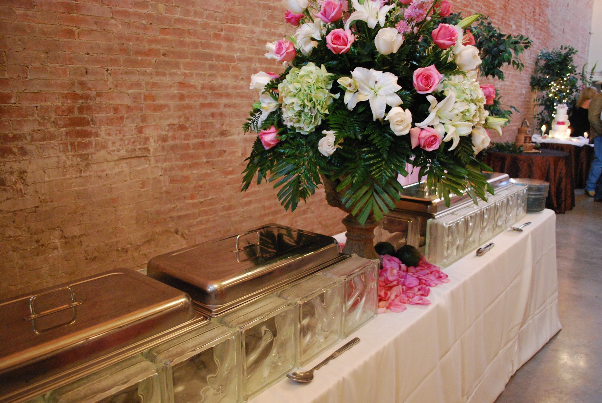 Floral funeral spray on a casket beside a brick wall and white-draped table