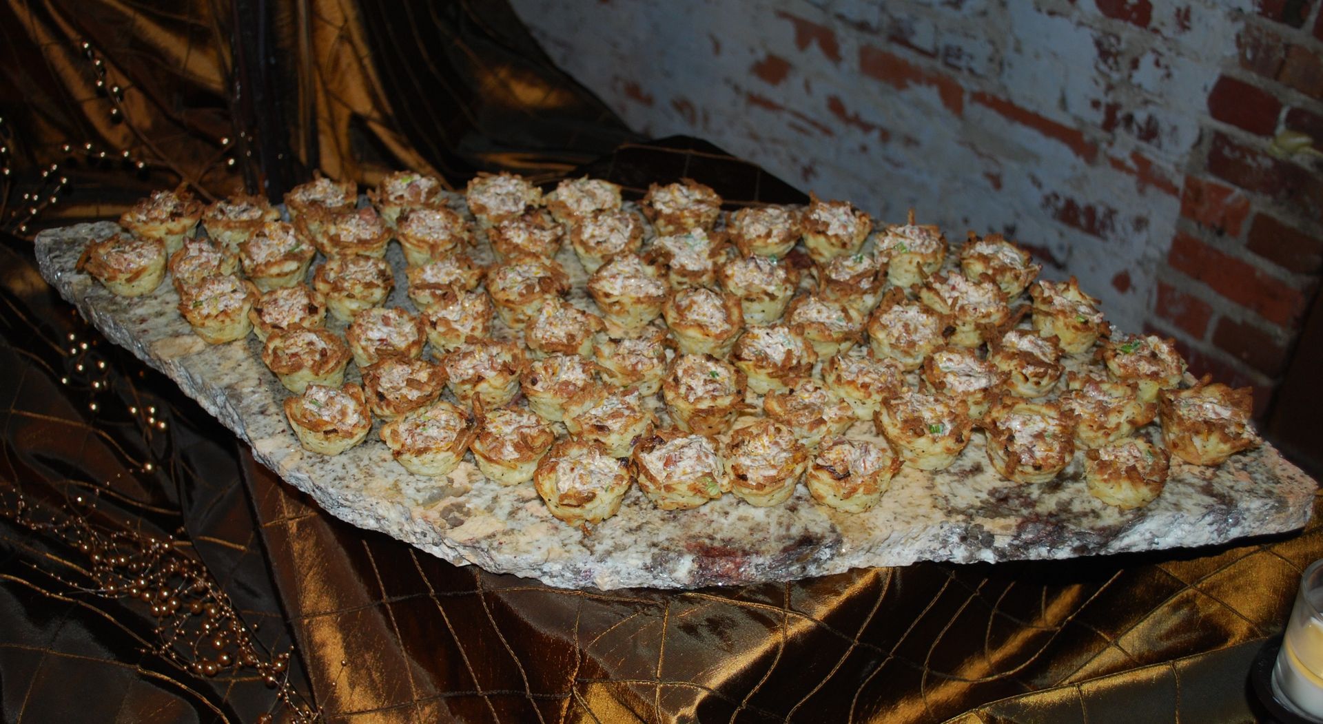 Tray of small baked seafood pieces on foil over an open flame in a brick-lined oven