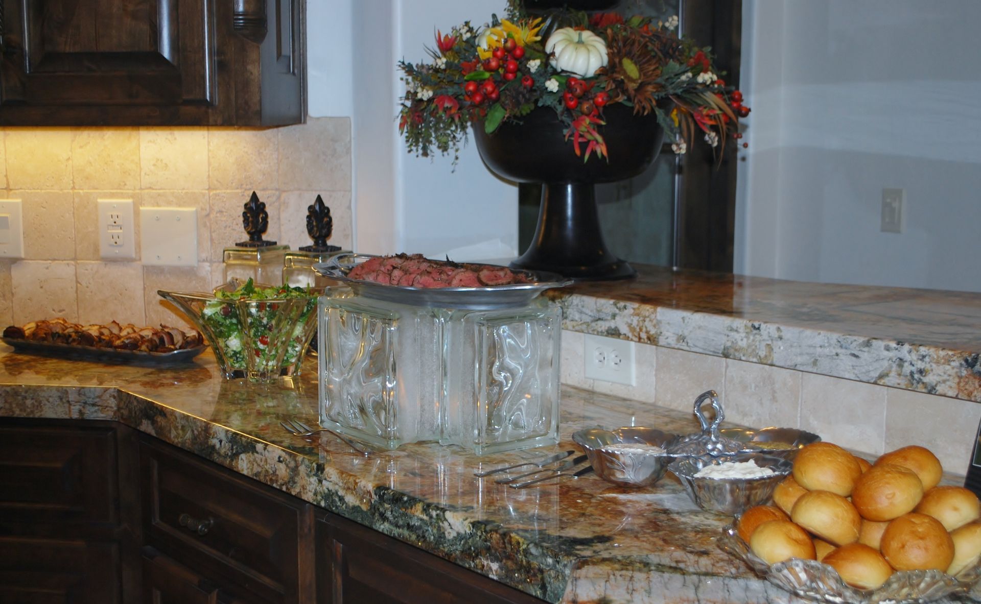 Kitchen counter with fruit bowls, flowers, and glass serving dishes on a marble countertop