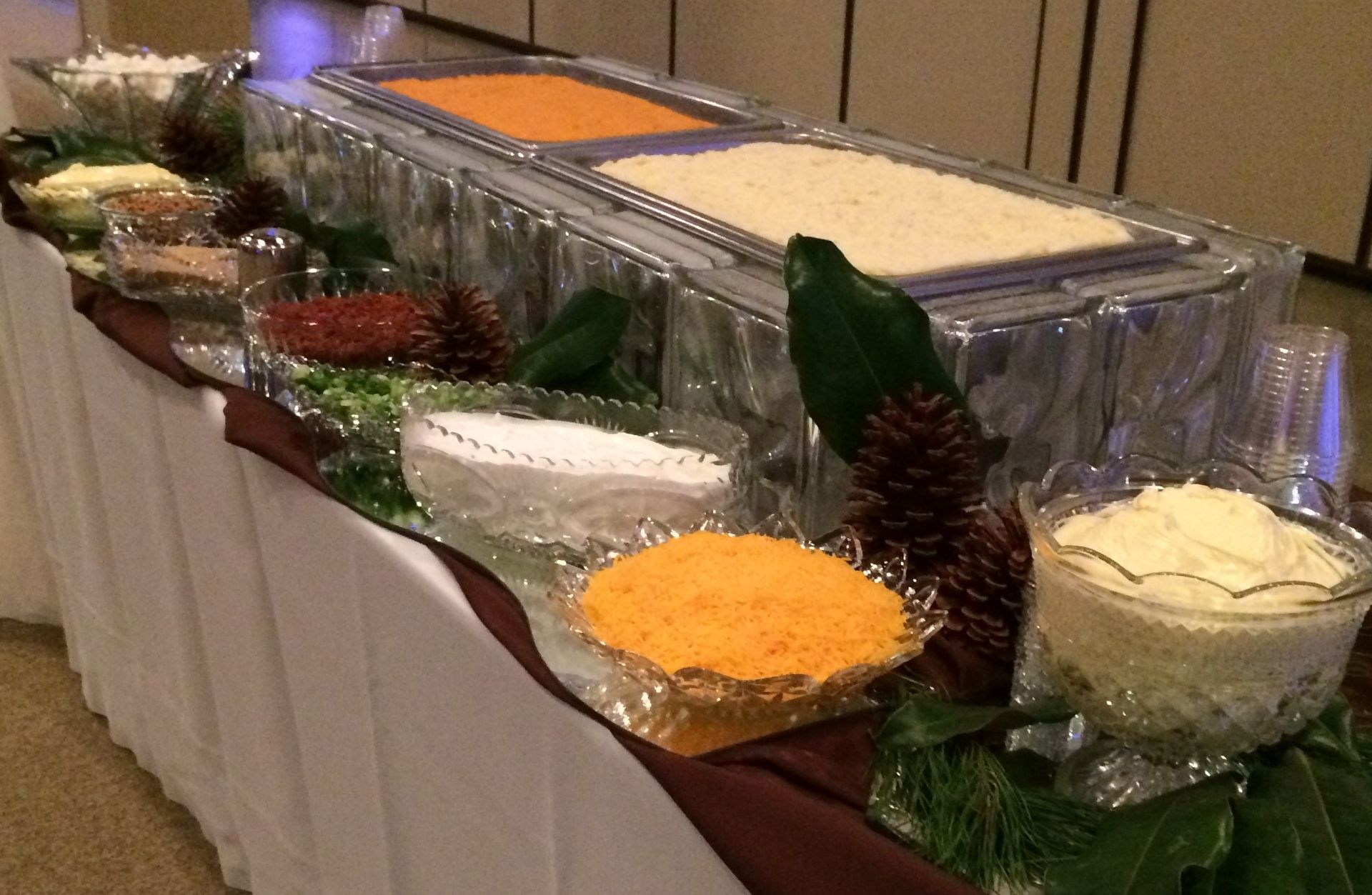 Buffet table with trays of food and bowls of salad and sides at an event