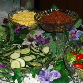 Assorted fresh vegetables and garnishes arranged on a decorative buffet table with flowers