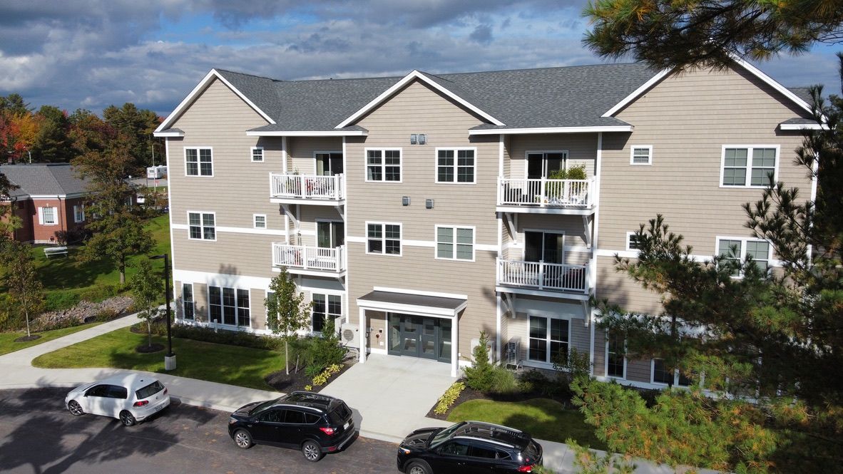 an aerial view of a large apartment building with cars parked in front of it .