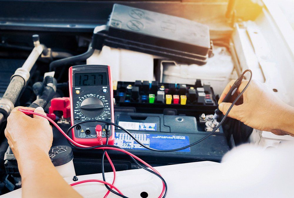 A person is working on a car battery with a multimeter — A Plus Automotive Electrical In Corowa, NSW
